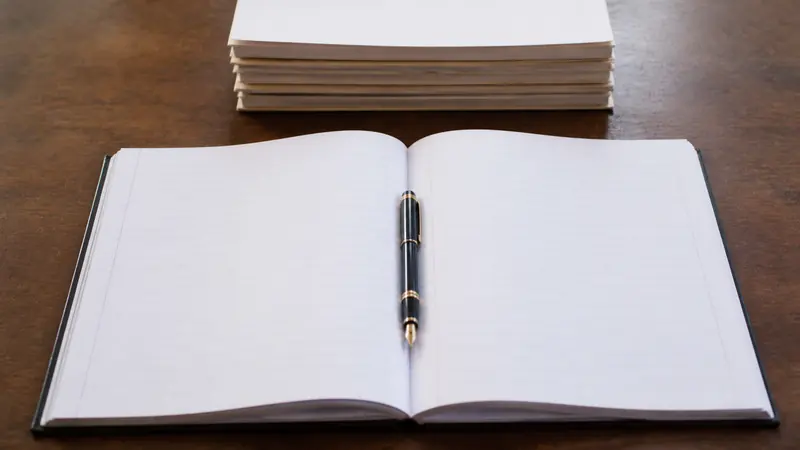 An open blank register and a pen on a school office desk in India, with paper files stacked to one side.