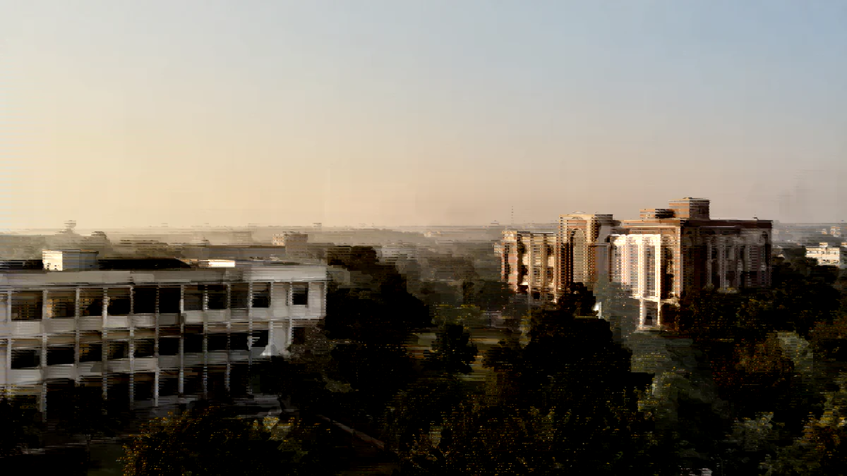 Two school campus buildings of different architecture seen across a green boundary at sunrise.