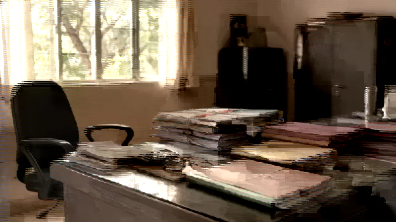 A school office desk stacked with separate bundles of files and ledgers awaiting reconciliation.